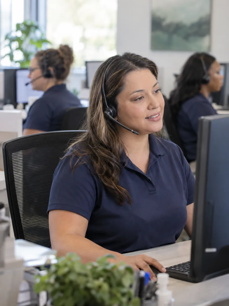 Patient coordinator in a dental group's central scheduling office taking a call on a headset
